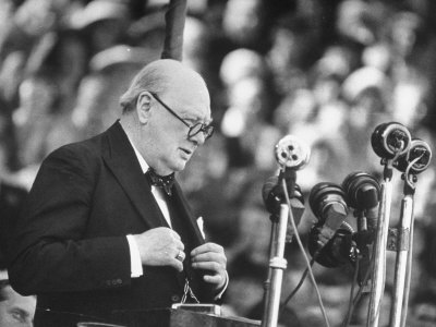 Winston Churchill giving speech glasses suit microphones.