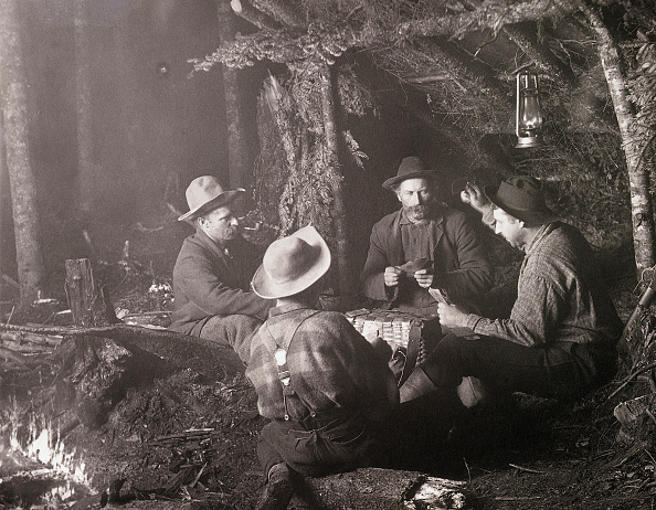 Vintage men outside playing cards in the woods.