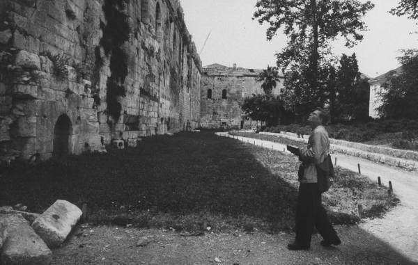 Vintage tourist looking at crumbling wall attraction.