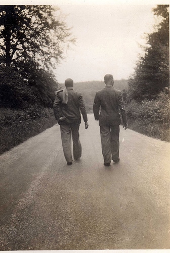 Vintage men friends walking side by side down road.